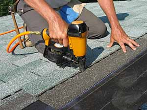 Roofing Contractor nailing in new shingles for repair